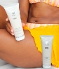 Woman in a bathing suit holding Neora’s best-selling Firm Body Contour Cream